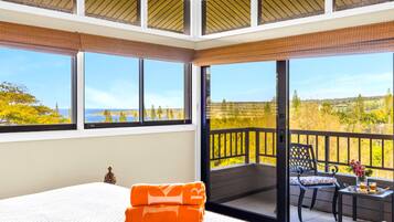 Una camera da letto con un letto grande, un balcone con tavolo e sedie, e vista sul paesaggio.