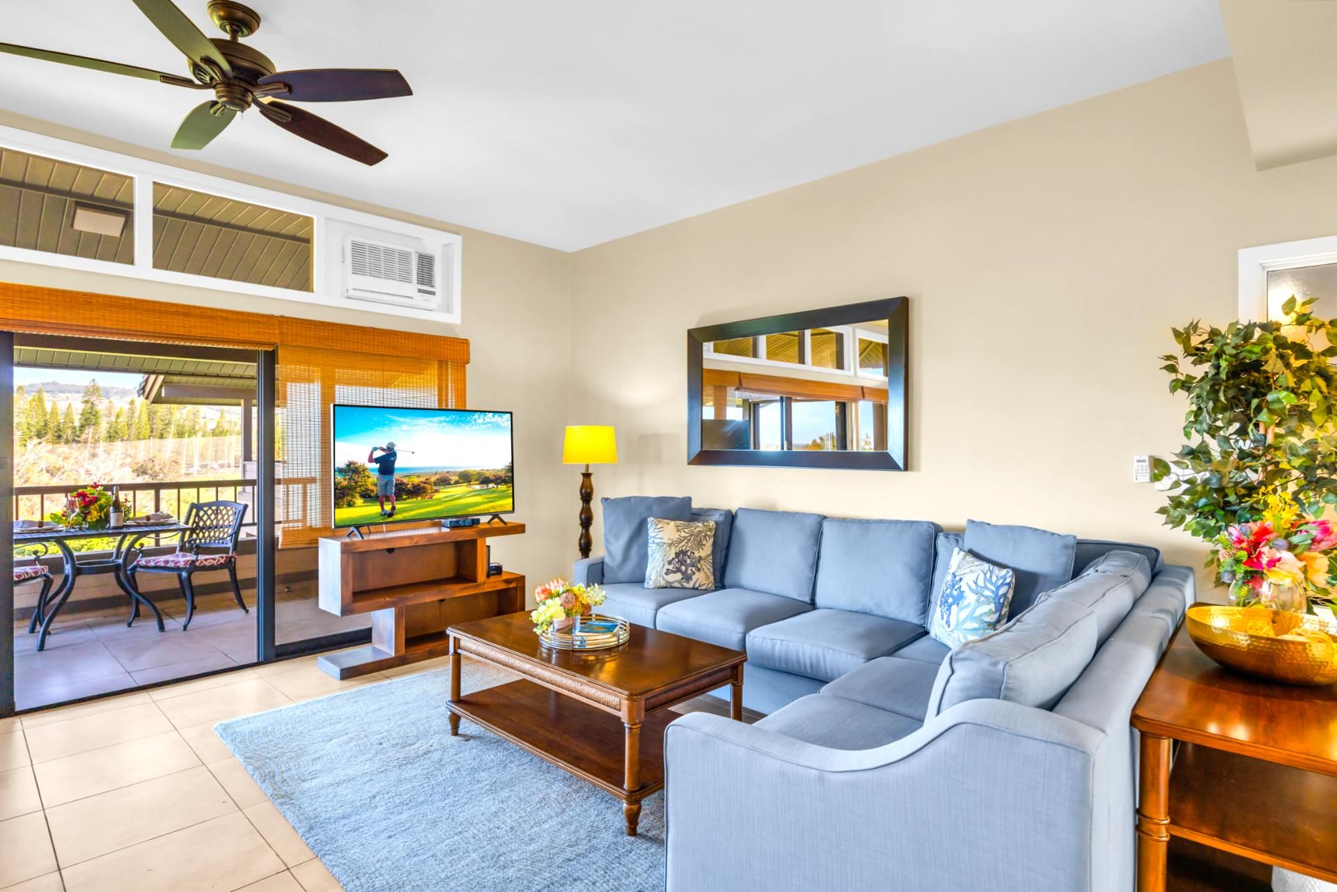 A living room with a sofa, coffee table, TV, and a balcony with a table and chairs.