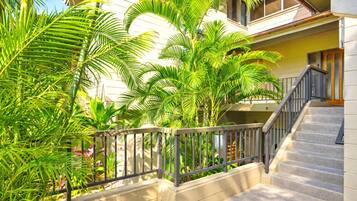 A residential building with a staircase, a balcony with a railing, and lush greenery.