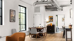 Ein moderner Essbereich mit einem Holztisch und Stühlen, einem schwarzen Schrank und einem Fenster mit Blick auf Grünflächen.
