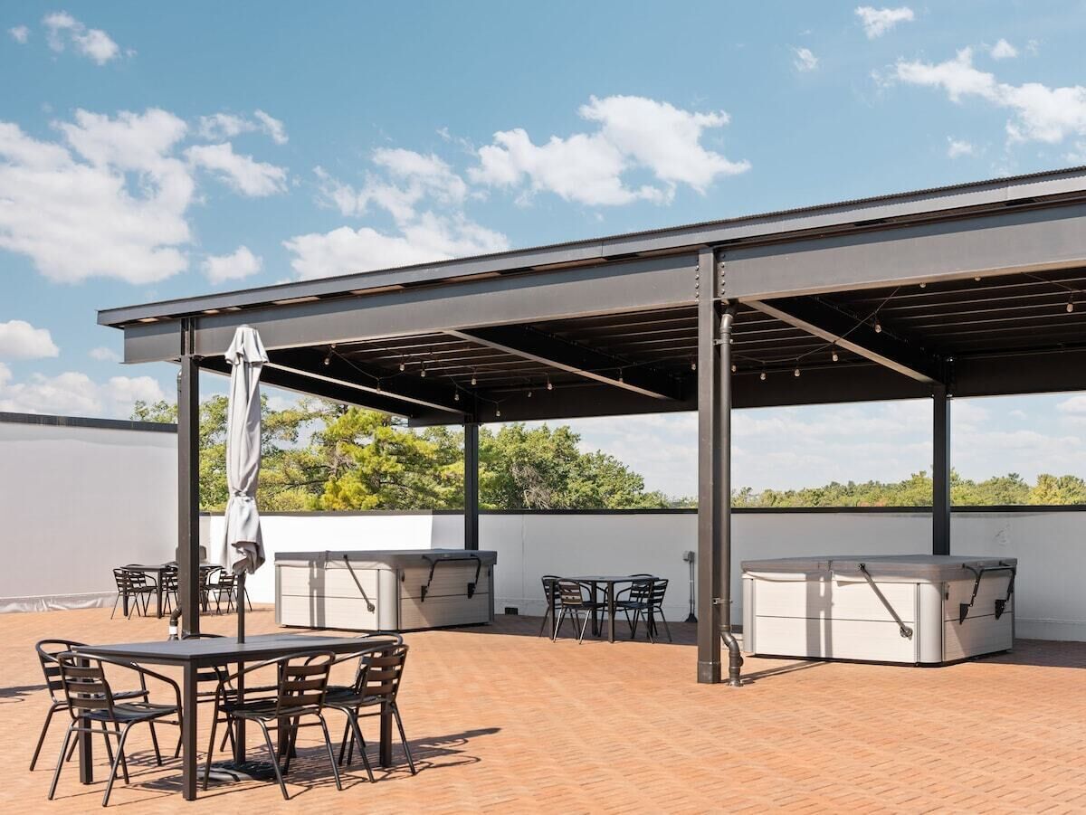 An outdoor patio with a covered seating area, a grill, and a table with chairs.