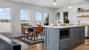 A modern kitchen with a large island, wooden cabinets, and a view of the outdoors. - Beach House - Lakefront with a Hot Tub! (Traverse City)
