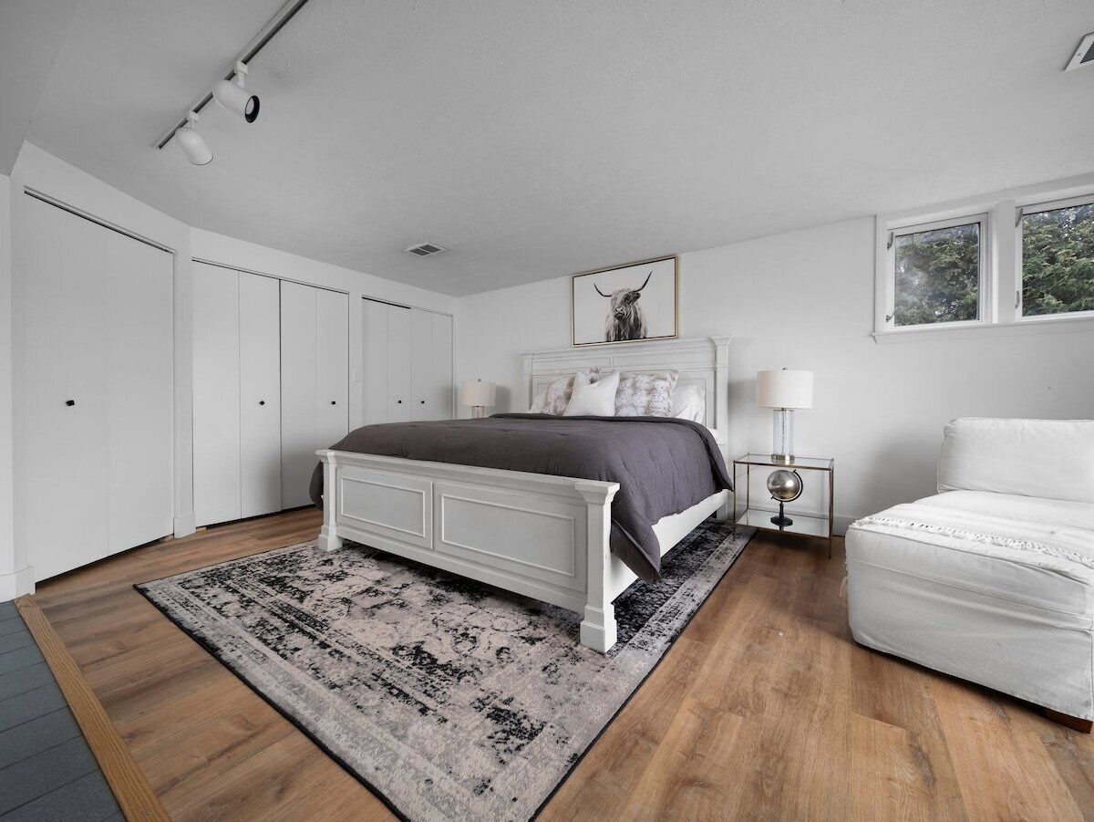 Une chambre à coucher avec un lit, des tables de chevet, une lampe et une fenêtre.