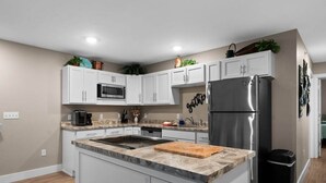 Una cucina moderna con mobili bianchi, un frigorifero in acciaio inossidabile e un piano di lavoro in granito.
