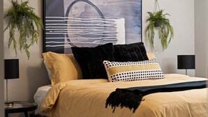 Una camera da letto moderna con un letto grande, due comodini, una lampada nera e un'ampia pittura astratta sulla parete.