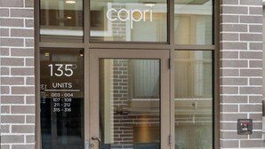 Ein Hotel Eingang, auf der Glastür steht der Name 'capri'. Innen ein Schild mit der Aufschrift '135 EINHEITEN' und darunter eine Liste mit Zimmernummern.