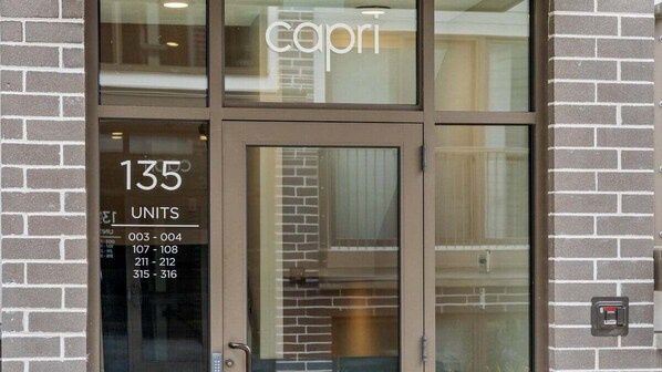 A hotel entrance with the name 'capri' on the glass door. Inside, there is a sign indicating '135 UNITS' with room numbers listed below.