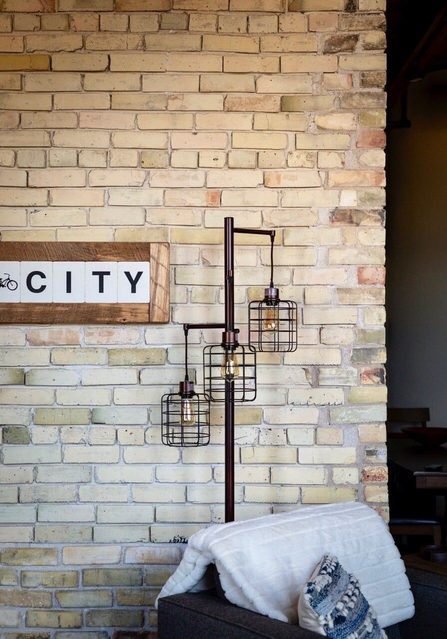 Een bakstenen muur met een bord waarop 'CITY' staat en een metalen lamp.