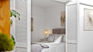 A bedroom with a bed, nightstand, lamp, and artwork on the wall.