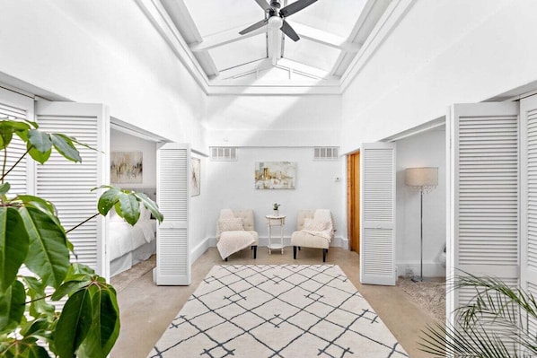 A bright hallway with a skylight, white walls, and a geometric rug.