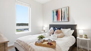 A hotel room with a large bed, a view of the outside, and a painting on the wall.