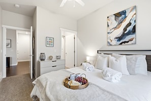Ein Hotelzimmer mit Bett, Frühstückswagen, einem Gemälde und einem Flur.