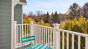 Een veranda met een witte balustrade en een enkele turquoise stoel.