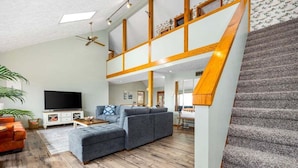 Un salon spacieux avec un grand canapé d’angle, un téléviseur à écran plat et un escalier doté de rampes en bois.