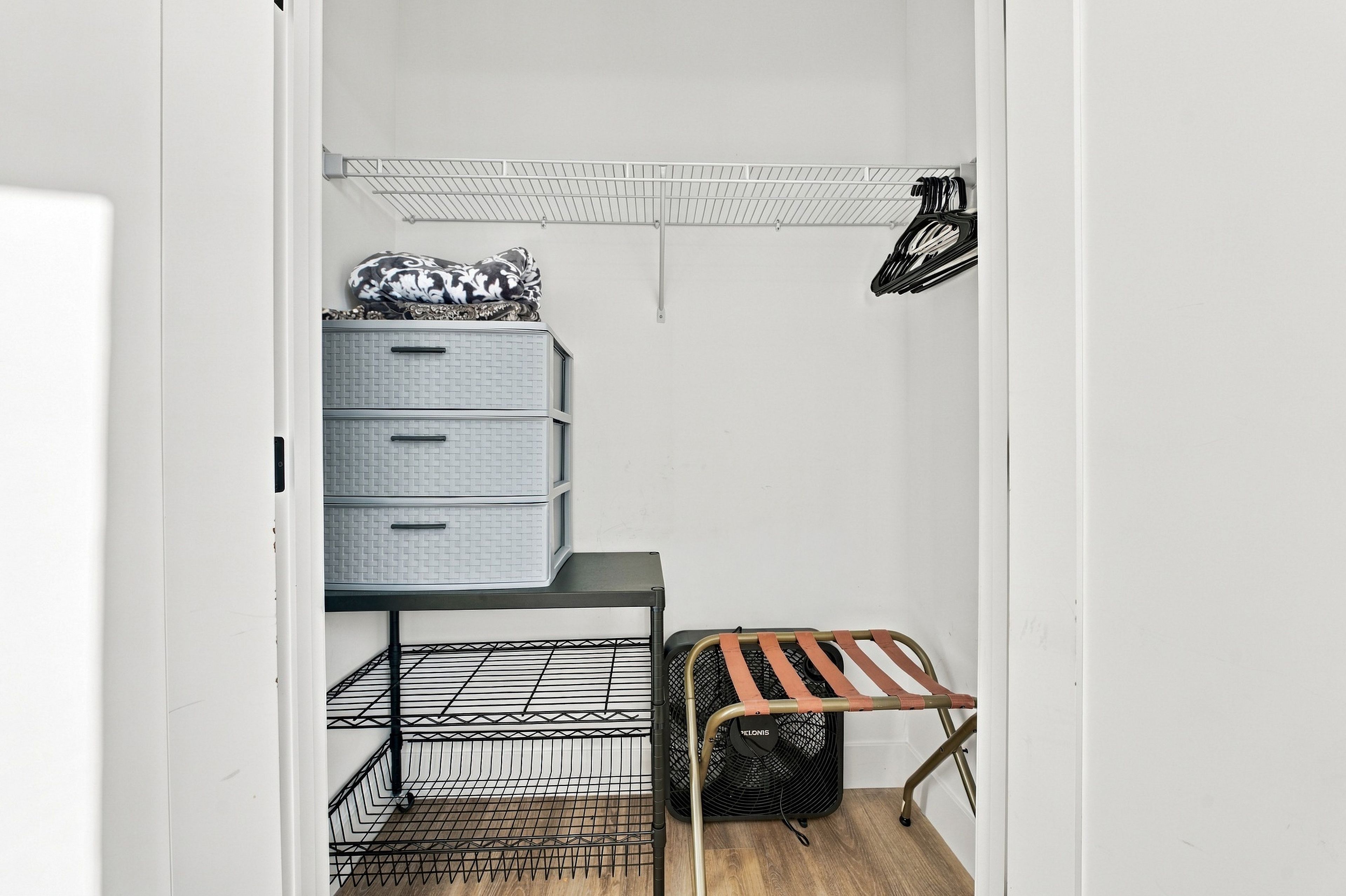 Ein begehbarer Kleiderschrank mit einem Metallgestell, einer Holzbank und einer Kommode mit Schubladen.