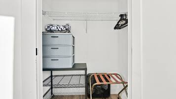 A walk-in closet with a metal rack, a wooden bench, and a storage unit with drawers.
