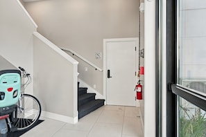 Un escalier menant à une porte, avec un extincteur fixé au mur.