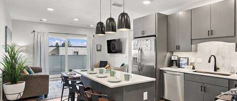 A modern kitchen with a central island, stainless steel appliances, and a dining area with bar stools.