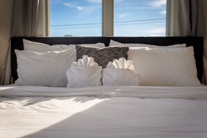 A neatly made bed with white linens and two towels placed on the pillows. - Cityscape Condo: New in Downtown Traverse City! (Traverse City)