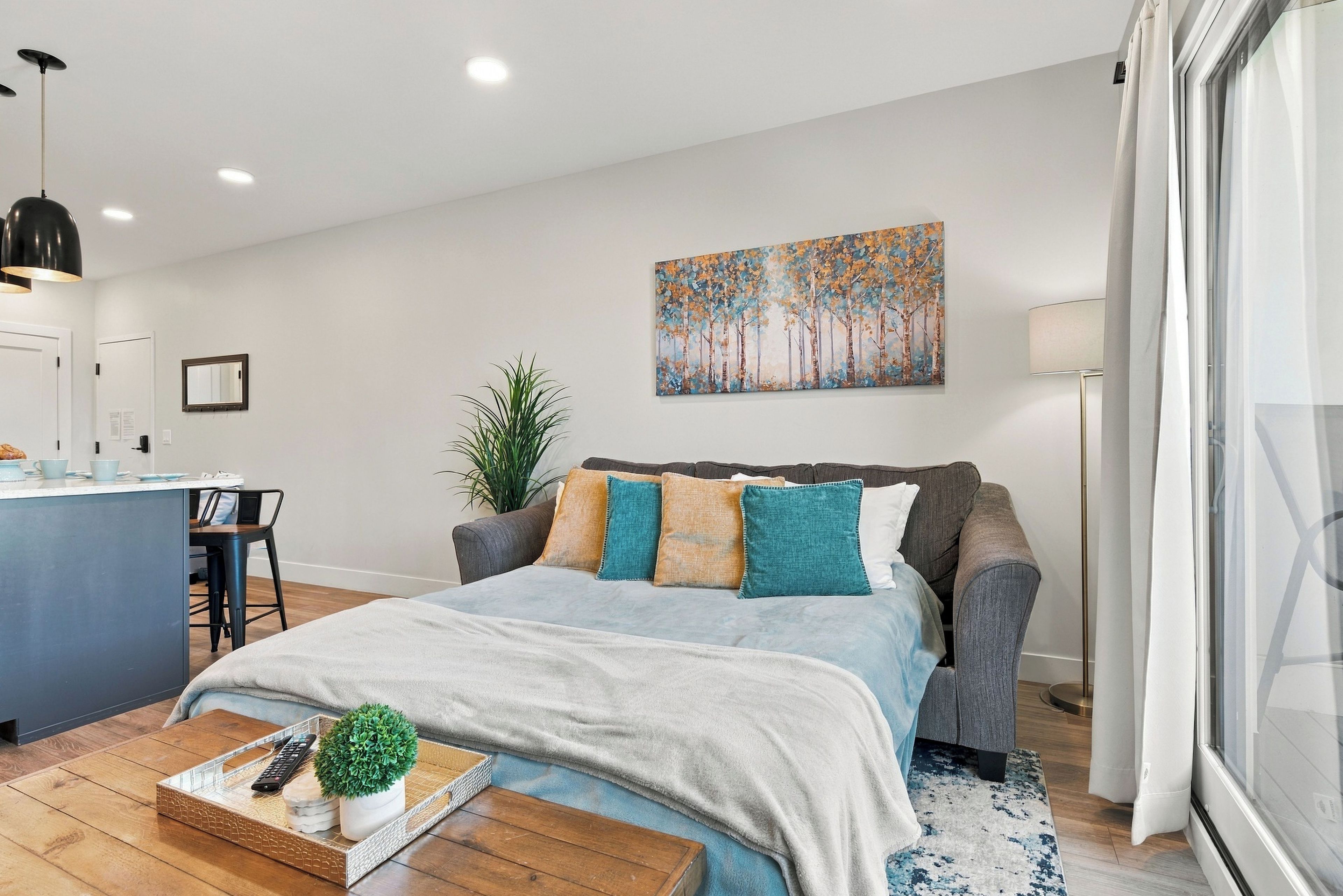 Een moderne slaapkamer met een bed, nachtkastje en een schilderij aan de muur.
