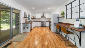 A modern kitchen with wooden flooring, white cabinets, and a built-in oven. - Bayside Bungalow: West Bay Views Minutes to TC (Traverse City)