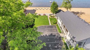 A hotel with a beach view, a parking lot, and a grassy area with lounge chairs. - Newly Remodeled Bayview Cabin 6! (Traverse City)