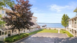 A coastal hotel with a parking lot, a covered outdoor seating area, and a view of the sea. - Newly Remodeled Bayview Cabin 6! (Traverse City)