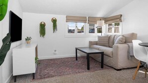 A modern living room with a sofa, a coffee table, a TV, and a small side table. - #01 Beach Bungalow at Lakeshore Resort (Traverse City)