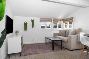 En moderne stue med sofa, sofabord, fjernsyn og et lille sofabord.