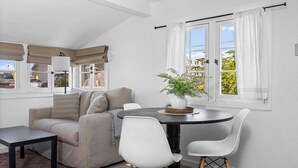 A modern living room with a sofa, two white chairs, a round table, and a potted plant. - #01 Beach Bungalow at Lakeshore Resort (Traverse City)