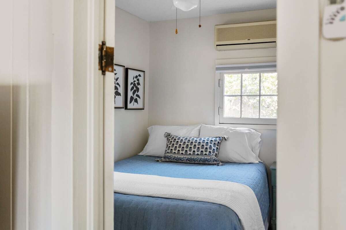 A bedroom with a bed, a window, and wall art.