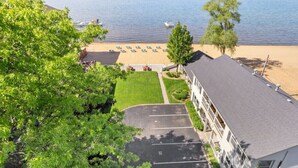 Ein Gebäude mit Parkplatz, Rasenfläche und Strand mit Liegestühlen.