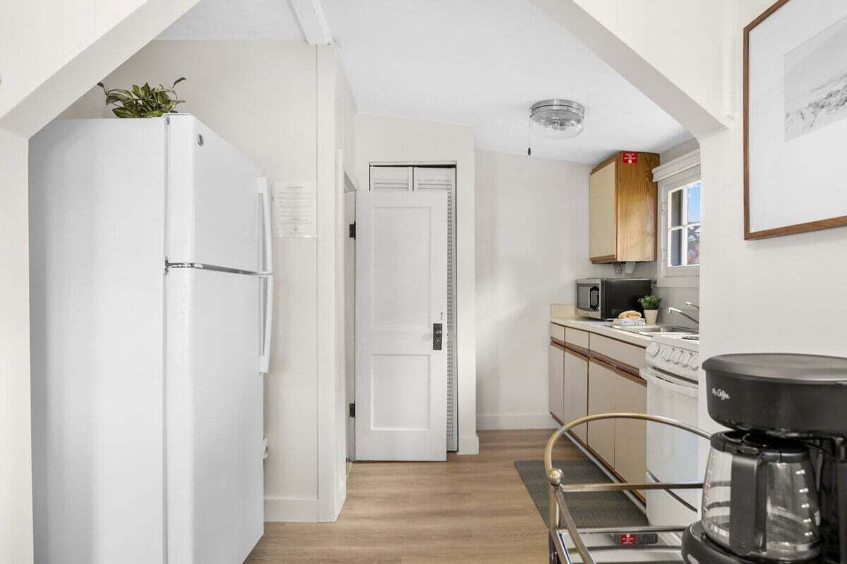 A narrow kitchen with white cabinets, a microwave, and a coffee maker.