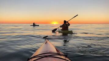 A kayak on calm water with a sunset in the background.