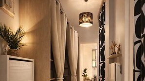 A hallway with a wooden cabinet, beige curtains, a hanging light fixture, and a patterned wall. - RARE Paris XV- ideal location 🏠 House with large courtyard (Paris)