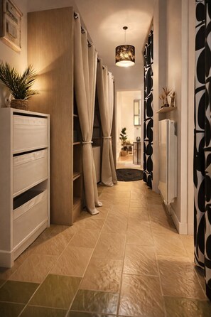 A hallway with a wooden cabinet, beige curtains, a hanging light fixture, and a patterned wall. - RARE Paris XV- ideal location 🏠 House with large courtyard (Paris)