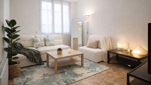 A modern living room with a sofa, a coffee table, a side table with lamps, and a large window. - RARE Paris XV- ideal location 🏠 House with large courtyard (Paris)