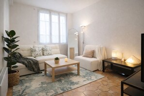 A modern living room with a sofa, a coffee table, a side table with lamps, and a large window. - RARE Paris XV- ideal location 🏠 House with large courtyard (Paris)