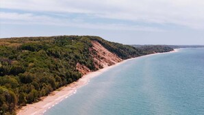 Eine Küstenlandschaft mit Strand und bewaldeten Hügeln.
