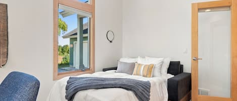 A bedroom with a bed, a chair, a door, and a window.