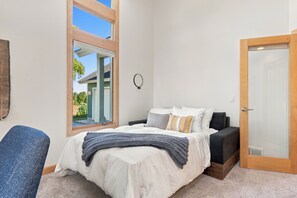 Un dormitorio con cama, una silla, una puerta y una ventana.