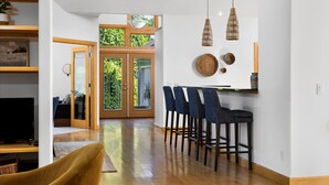 A modern kitchen with a bar area, wooden flooring, and a large window with a view of greenery. - Seven Hills Estate on Old Mission (Traverse City)
