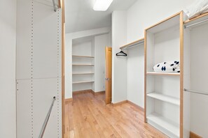 Un vestidor con suelo de madera, estanterías metálicas y una barra para colgar ropa.