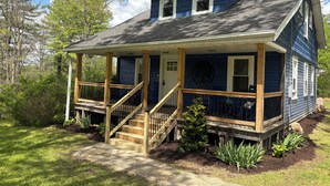 A two-story house with a porch, wooden stairs, and a small garden.