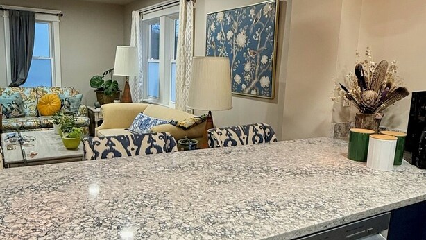 A modern kitchen with a granite countertop, dark cabinetry, and pendant lighting.