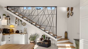 Eine moderne Küche mit weißen Schränken, einer Holz Arbeitsplatte und einer Treppe mit einem geometrischen Metallgeländer.