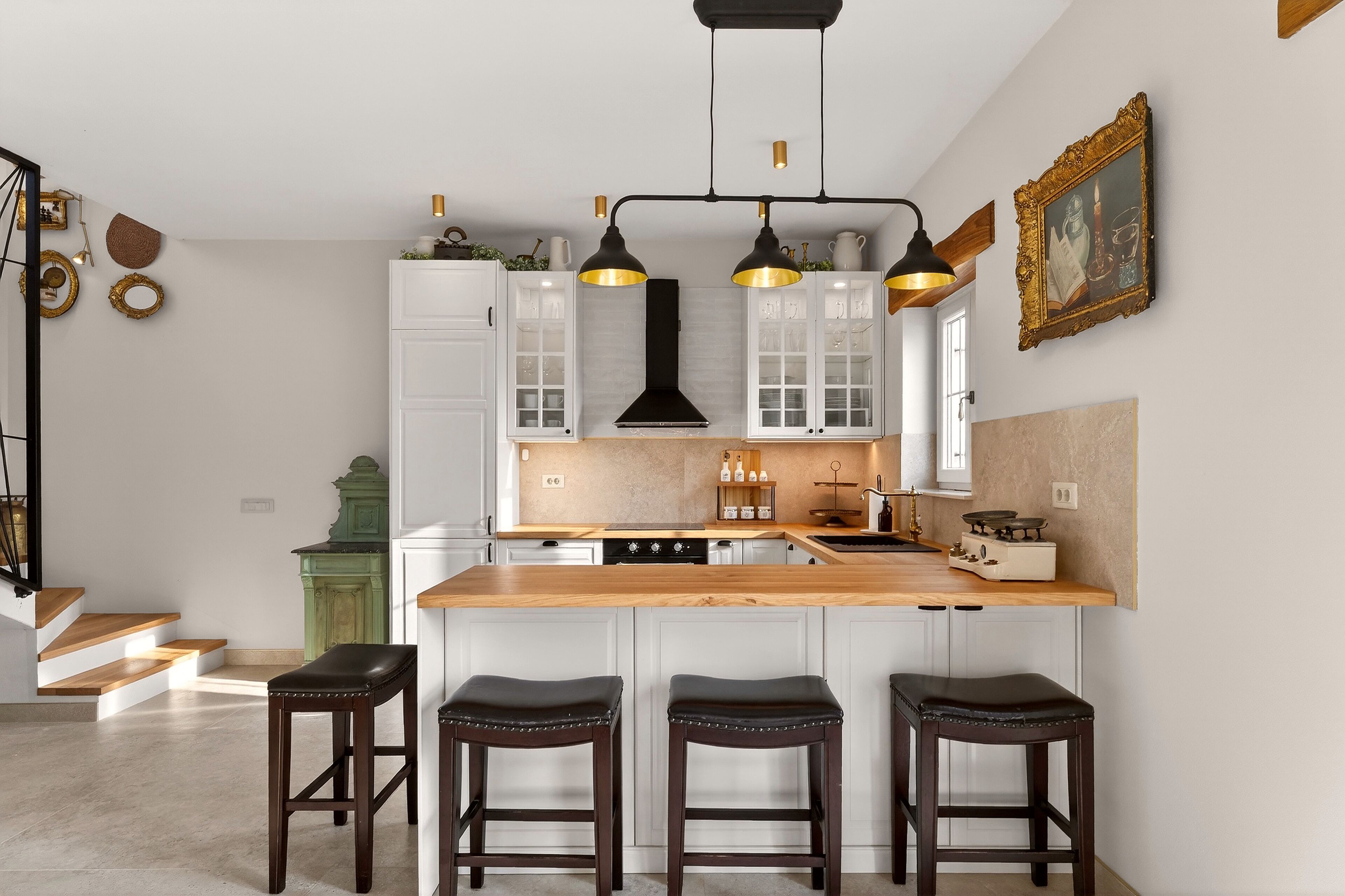 A modern kitchen with white cabinets, a wooden island, and three bar stools.