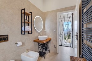 A modern bathroom with a freestanding bathtub, a wooden vanity with a white sink, a round mirror, and a towel rack. - Vacation home Amore near Motovun, Istria (Sovišćina)