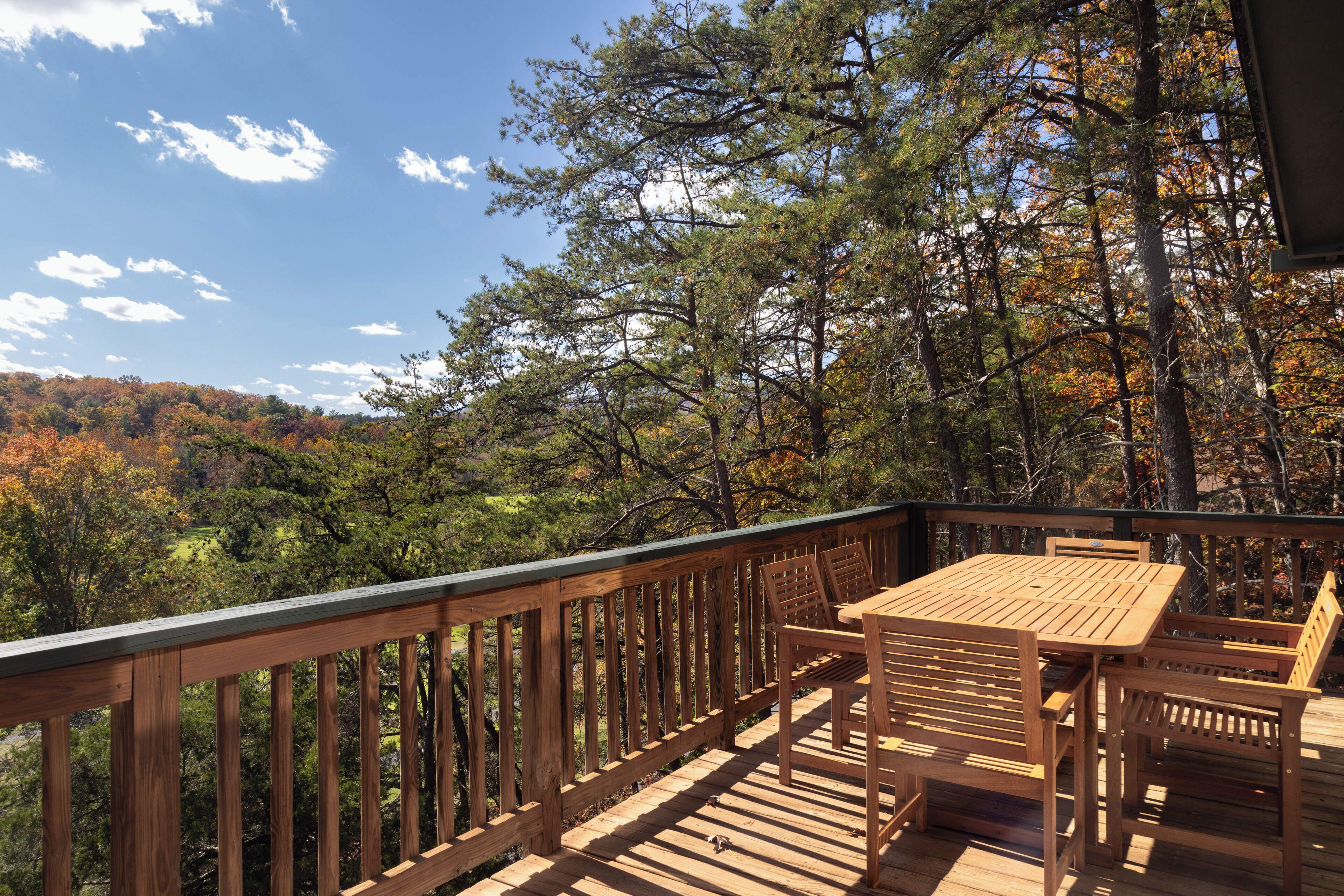 Une terrasse en bois avec une table et des chaises, donnant sur une zone boisée.