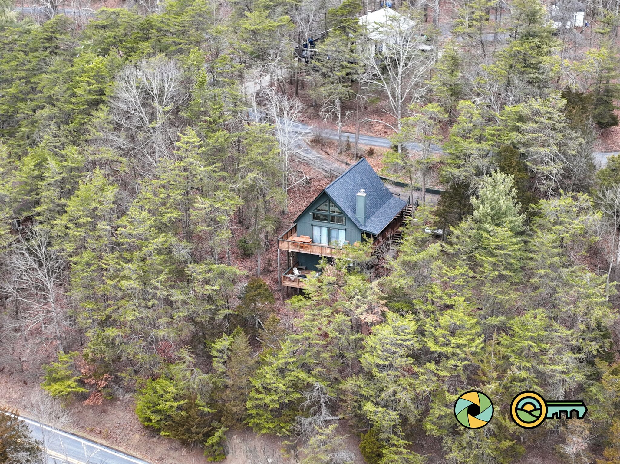 A house surrounded by dense forest, with a visible deck and large windows.